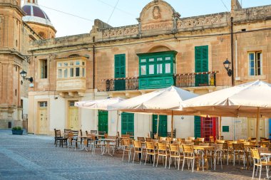 Malta 'nın popüler balıkçı köyü Marsaxlokk' taki kilise yakınlarındaki kasaba meydanındaki sokak restoranları ve kafeler.