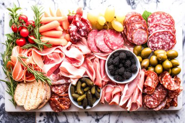 Dilimlenmiş et, çeşitli peynirler, taze meyveler ve süslerle dolu taşralı bir şarküteri tahtası. Eğlenmek için mükemmel.