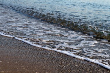  Kumsal kumsalı. Kumlu bir sahilde el salla. Arka plan için su manzarası. Doğa konsepti yumuşak odaklanma. Dalga hareketi.