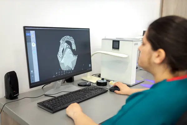 牙医在计算机上使用牙科扫描软件制造假牙 从事假肢工作的牙科医生 图库照片