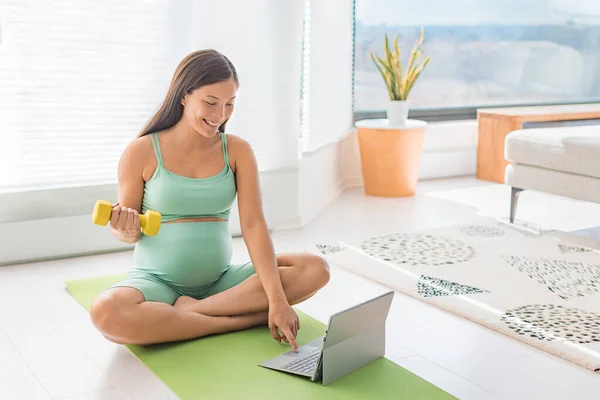 怀孕妇女在家里用笔记本电脑参加网上的女子女教育课程 健美力量训练练习与哑铃重量 身体锻炼手臂卷曲 第二和第三次运动很容易 — 图库照片