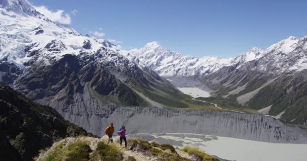 ニュージーランドマウント山の中でハイキングを踏みハイカーとクック自然景観 アオラキ クック国立公園のハイキングコースを歩くカップル レッド エピック スローモーション — ストック動画