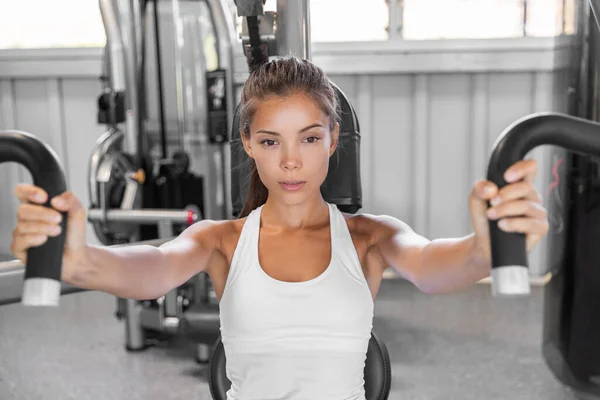 Gym workout Asian woman focused and motivated training on pec deck chest press fly machine. Fitness workout.