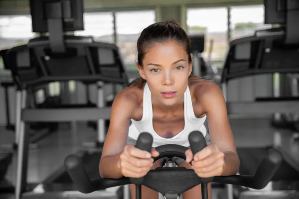 Gym fitness class fit woman riding spin bike doing hiit exercise cycling doing cardio workout biking on indoors gym bike. Girl cyclist working out interval training on bicycle. weight loss.