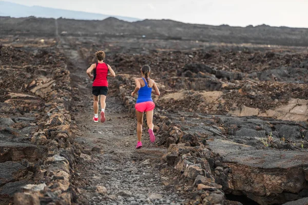 Trail run runners couple fit athletes training together running in volcanic field for marathon race. Male and female people endurance workout.