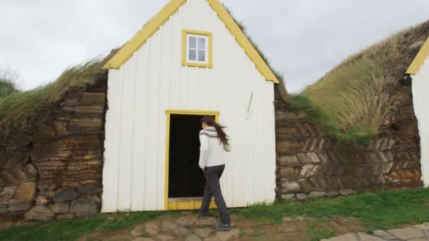 アイスランドの観光客による古い農家ラウファ グラムバー農場スカガファジュドゥールのVarmahlid Skagafjordurにある民俗博物館芝屋根の家 アイスランドの観光地とアトラクションのランドマーク アイスランドのセーターを歩く女性 — ストック動画