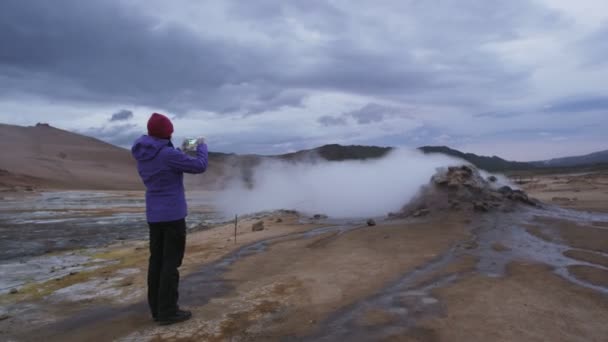 アイスランド火山泥岩温泉ランドマーク目的地 ナマフジャル ハバーロンドンまたは泥プール温泉やフマロール 美しいアイスランドの自然 スマートフォンで写真を撮る女性観光客 — ストック動画