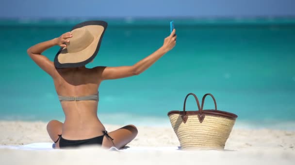 아름다운 여자가 셀카를 해변에 가져가다니 여행은 해변에서 일광욕을 동안의 개념이다 — 비디오
