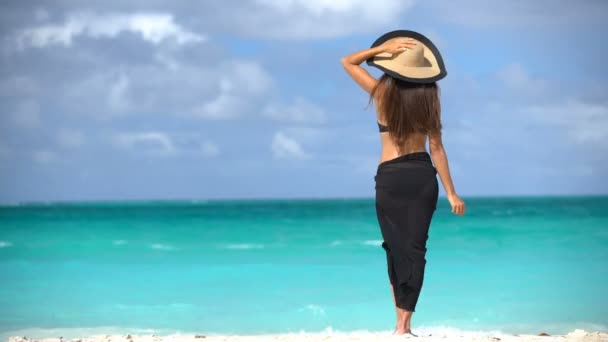 身穿黑色比基尼和沙隆的女人站在海滩上 优雅性感的女性穿着黑色比基尼和沙隆在海滩上 在加勒比地区的度假胜地 妇女们正在尽情享受暑假 — 图库视频影像