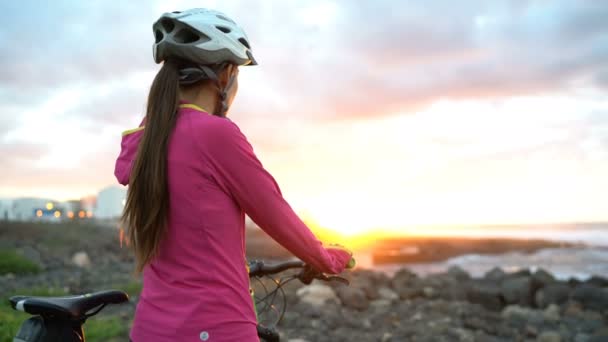 年轻女子Mtb骑自行车骑山地自行车 日落时戴着自行车头盔看风景 戴自行车头盔的漂亮女人骑单车后在放松的同时享受大自然 — 图库视频影像