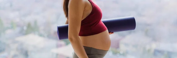 妊娠中のヨガや運動中妊娠中の女性は プロフィールにヨガマットを保持美しい赤ちゃんのバンプ腹を示す出生前ヨガクラスに行きます 健康な妊娠生活を送る女性 パノラマバナー — ストック写真