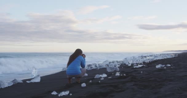 摄影师在冰岛钻石沙滩上与冰合影 在冰岛南部海岸的奥库沙隆冰山海滩 Okulsarlon Iceberg Beach 拍摄的女性照片 红色Epic慢速运动 — 图库视频影像