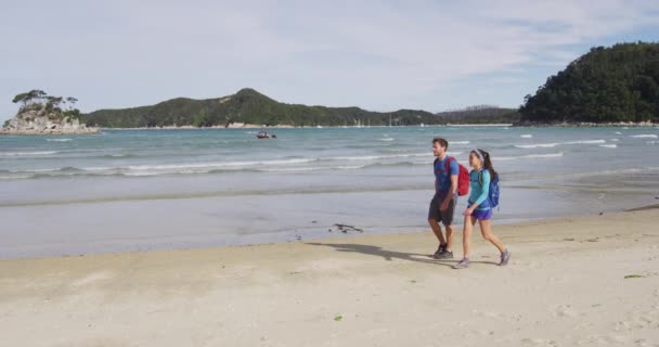 新西兰海滩Abel Tasman国家公园 人们在新西兰托伦特湾著名的海滨小径上徒步旅行 旅行和背包旅行 年轻夫妇背着背包 红色Epic慢速运动 — 图库视频影像