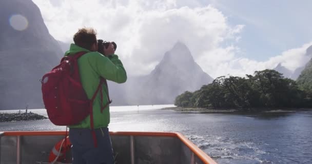 クルーズ船ツアー中にニュージーランドのフィールドランド国立公園でミルフォードサウンドとミッレピークの写真を撮る旅行写真家 — ストック動画