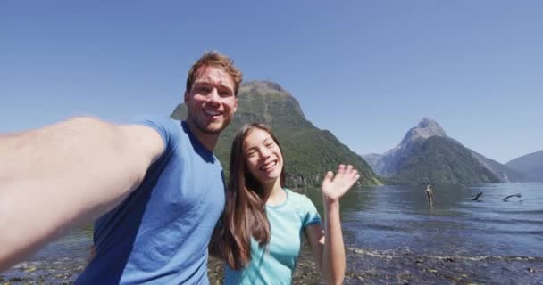 一对夫妇在新西兰的旅行中自拍视频 Milford Sound 在新西兰的Fiordland 快乐的男女们带着坦率的自画像视频向旅行的摄像机挥手致意 — 图库视频影像