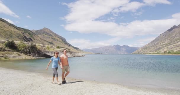 Новая Зеландия Путешествует Счастливой Туристической Парой Прогуливаясь Пляжному Берегу Озера — стоковое видео