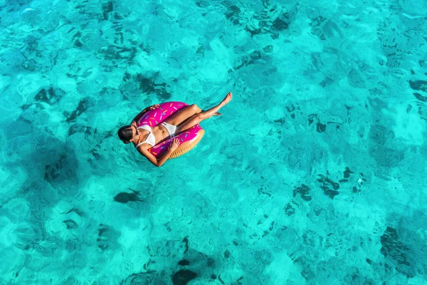 プールでリラックスしたビーチバケーションの女性は カリブ海の旅行夏にターコイズブルーの海の水の背景に浮かぶドーナツインフレータブルリングを浮かべます 女の子でホワイトビキニ上ドローンビュー — ストック写真