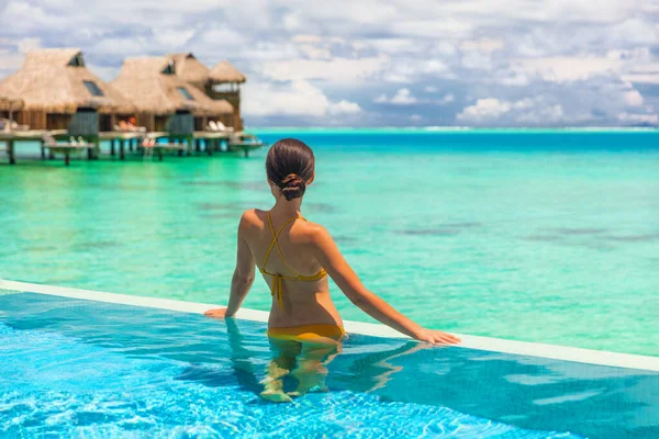 奢华的落水平房酒店房间里 有无限大的游泳池女士看着蓝色的大海 热带旅行暑假生活方式 — 图库照片