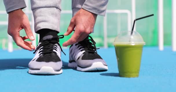 健美的男人准备好了用绿色软糖果汁脱毒饮料系跑鞋 用早餐蔬菜汁给跑步训练员包扎 过着积极体育生活的人 — 图库视频影像