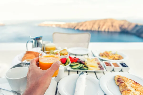 豪華な旅行リゾート朝食サントリーニ島 オア島 ギリシャの素晴らしいバルコニービューを持つ豪華なホテルレストランでルームサービスで ヨーロッパの休暇食の自撮り 朝のオレンジジュースを飲む男 — ストック写真