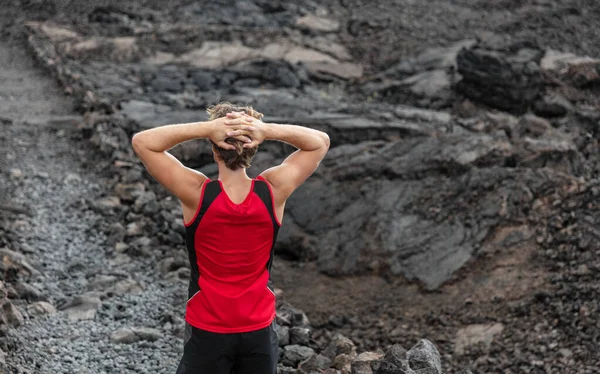 マウンテントレイルランで疲れたランナーは 屋外の夏のハワイの風景の黒い溶岩火山岩の道で背もたれの痛みで休んで休憩を取ります — ストック写真