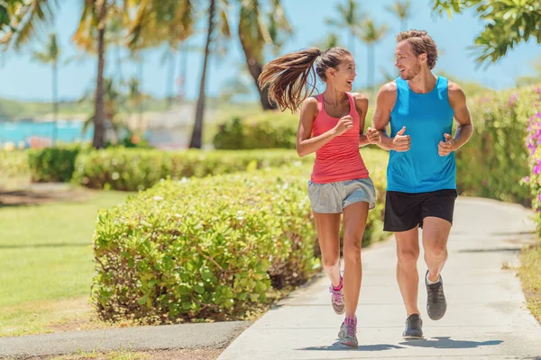 快乐的赛跑选手夫妇在城外的人行道上一起跑步 谈论训练 妇女和男子慢跑健康的有氧运动生活方式 图库图片