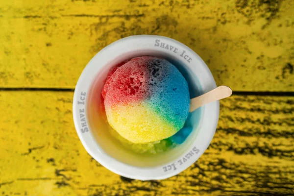 3色の染料で氷ハワイ地元の食べ物のハワイの雪のコーンを剃ります 冷凍デザートフードレトロな黄色のテーブルの上のボウルのビュー — ストック写真