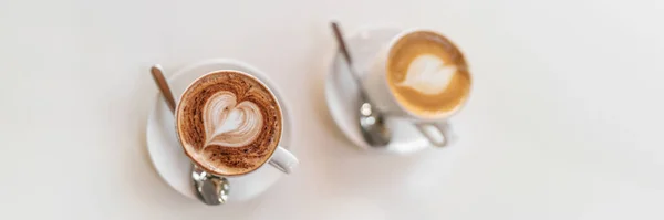两个咖啡杯顶部的白色桌子横幅背景 拿铁艺术咖啡和卡布奇诺热饮全景 免版税图库照片