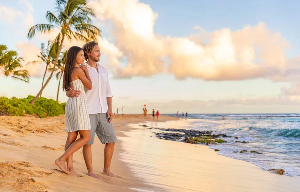 ロマンチックなサンセットビーチでのカップルは 米国のカウアイ島でのハワイの夏の旅行休暇中にリラックスして歩きます 白いドレスのアジアの女性 リネンシャツの男 — ストック写真