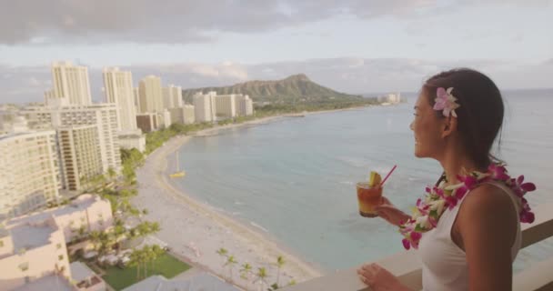 ハワイワイキキビーチ観光客がカメラを見て舞タイドリンク応援を楽しんでいます高級リゾートでのホノルル市内旅行休暇の女性 伝統的な花のレイを身に着けている夕日のバルコニービュー — ストック動画