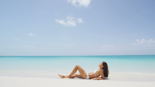 晒黑的女人在夏天的海滩度假日光浴中放松 穿着白色比基尼的性感的年轻成年人躺在沙滩上 为热带旅游目的地的概念提供天空版权空间 慢动作 — 图库视频影像