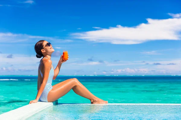 夏の健康的な食事女性バランスの取れた食事減量ビキニボディライフスタイルのためのデトックスニンジンジュースを飲む 幸せな生活の女の子楽しむ日日焼けの休日によってプールのトロピカルホテル — ストック写真