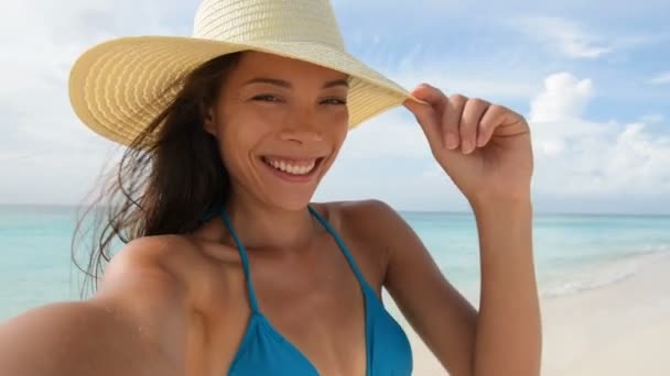 漂亮而快乐的年轻女子在海滩上快乐地自拍 一个无忧无虑的女孩享受暑假的画像 度假时 快乐的女性穿着蓝色比基尼 躺在完美的白色沙滩上 — 图库视频影像