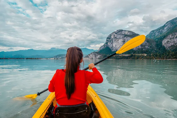 女子皮划艇在斯卡拉米什划桨在皮划艇在豪湾一个峡湾周围是山 加拿大不列颠哥伦比亚省生活在积极的室外健康生活方式中的人 图库图片