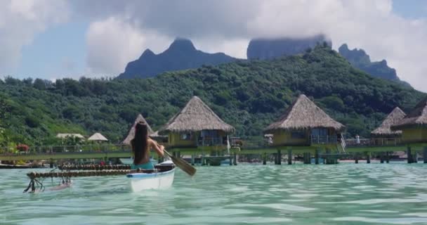 アウトリガーカヌー レクリエーションやウォータースポーツに使用される伝統的なフランス領ポリネシアのアウトリガーカヌーでパドリング女性 ボラボラから有名な大手町山と水上バンガローリゾートホテルでクリップ — ストック動画
