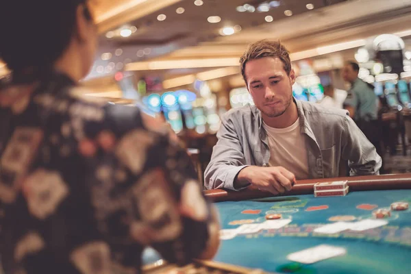 赌场的年轻人拿着纸牌和薯片在桌上玩21点 商人与赌徒的室内肖像 — 图库照片