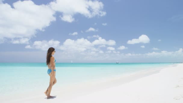 ビーチでの休暇旅行ビキニの女性は 水着を着て素晴らしい完璧な白い砂浜でターコイズブルーの海の水でリラックスしてビーチを歩く ゴージャスなビキニモデルとともにビーチボディ — ストック動画