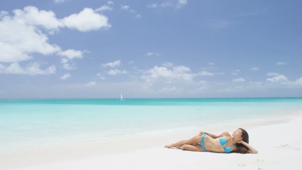 カリブ海の熱帯の豪華な目的地でビーチで日光浴に横たわっているビーチの休暇に日焼けリラックスしたセクシーなビキニボディの女性 ファッション スキンケア太陽保護 減量の概念 — ストック動画