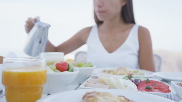 年轻女人把咖啡倒入杯子里 不同种类的健康食品在露台度假地供应 女的在度假时吃着美味的早餐 — 图库视频影像
