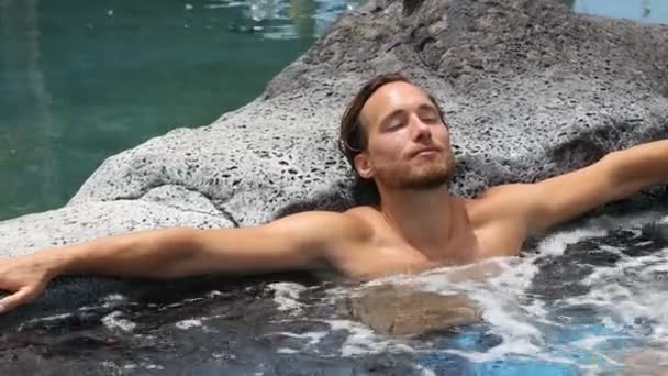 温泉疗养 男子在温泉度假胜地的室外温泉浴池里放松一下 度假旅行时 快乐的年轻男模在水里放松休息 — 图库视频影像