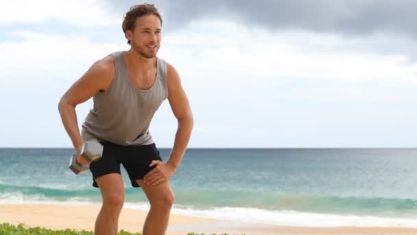 哑铃练习 男子单臂站立哑铃行练习 男子健身模特儿在海滩上进行户外运动 实际时间 — 图库视频影像