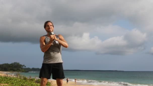 フィットネス運動 男はダンベルでツイスティングウッドチョップ運動を行います ダンベルを使用してビーチでフィットネスワークアウトを行うフィットネスモデルをフィット — ストック動画