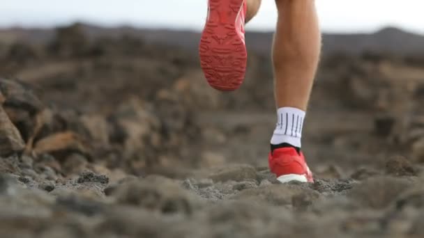 跑步者小径跑 跑鞋的关门 年轻的男性运动员在火山景观中慢跑 一个有决心的人在阳光灿烂的天气里穿着运动服在岩石田里锻炼 — 图库视频影像