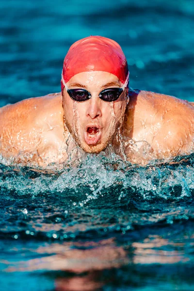 游泳的男人 男子游泳运动员做蝶泳动作 男子运动健美男子穿着泳衣和泳帽 在室外游泳池中刻苦训练 专业运动健身模式 — 图库照片