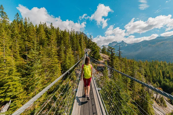 妇女在高山上远足时 跨过吊桥 景色迷人极了 加拿大旅游概念来自不列颠哥伦比亚省 公元前200年 在户外的天堂里 爬行的游客在令人叹为观止的大自然中 免版税图库图片