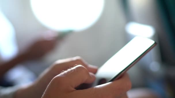 携帯電話を保持する出張旅行で機内無線Lanインターネットを使用して携帯電話上の飛行機の乗客の男のテキストメッセージ 5G技術デバイス 飛行機で携帯電話を使う二人 — ストック動画