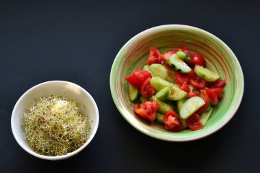 Gri arka planda salatalık, domates ve yonca filizli sebze salatası..