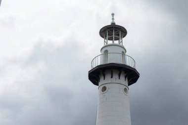 Yağmur mevsiminde bulutlu bir gökyüzünün arkaplanındaki deniz feneri.