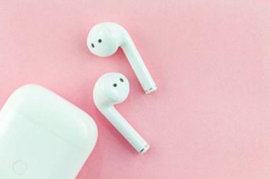 Pembe arka planda kablosuz kulaklık ya da bluetooth kulaklık..