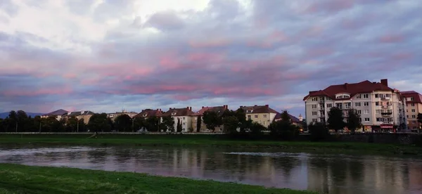Pink sky, sunset in cloudy weather, walk by the river